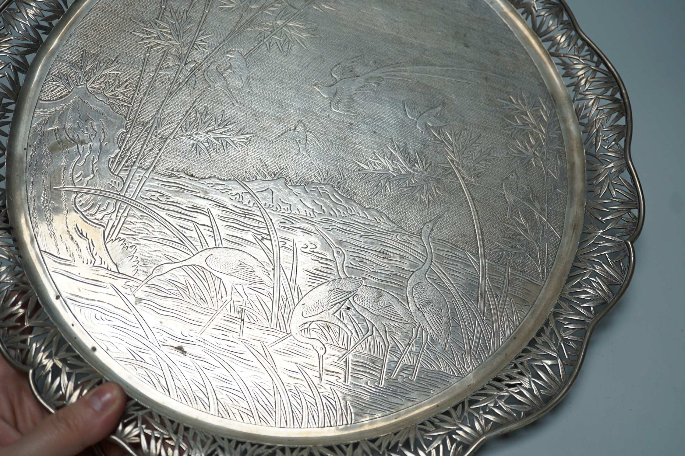 A Chinese Export white metal circular salver with pierced foliate wavy border and engraved with birds amongst reeds and bamboo, maker's mark, WHL, 33.7cm, 36oz.